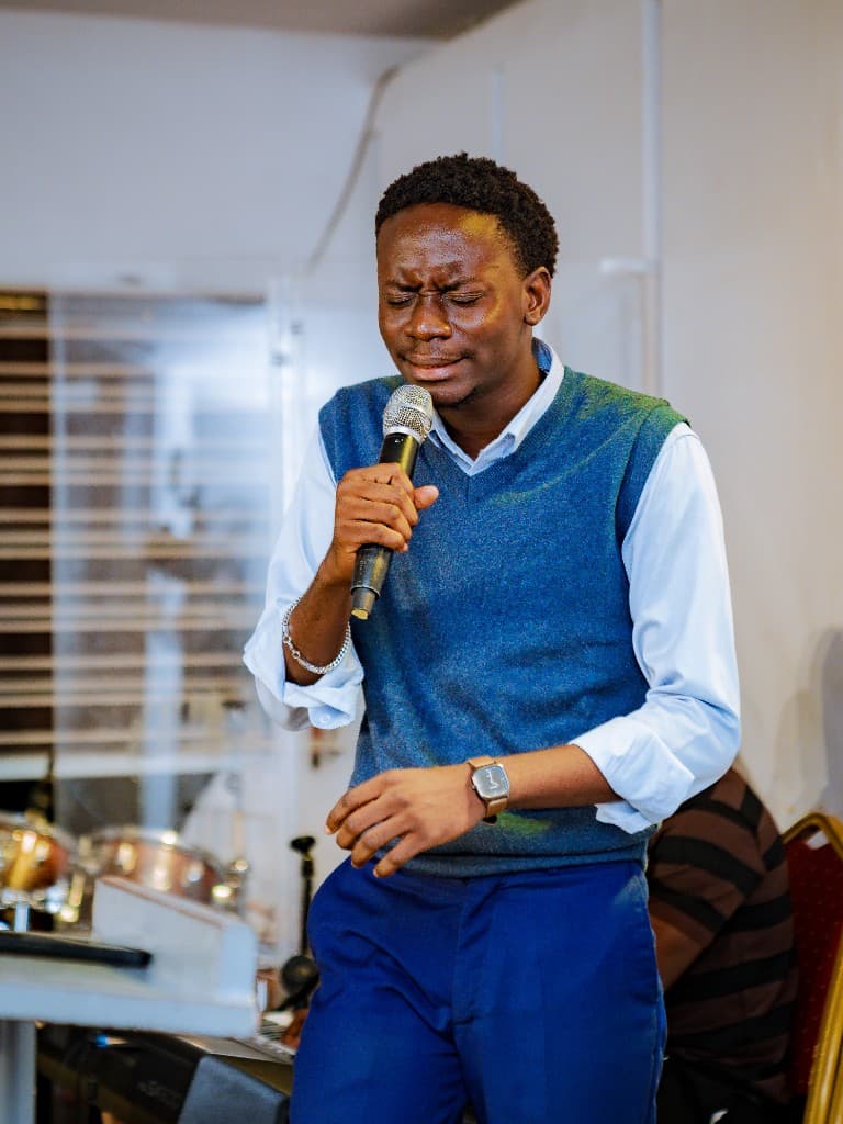 A young man leading worship with eyes closed, holding a microphone